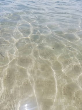 Bu fotoğraf, kıyı sükunetinin özünü yakalar, berrak suyun ılık güneş ışığında altın kuma nazikçe uzandığı yeri. Seni sakin ve iç huzur dolu bir yere naklediyorum..