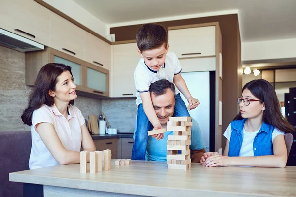 Uma família alegre joga jogos de tabuleiro em casa . — Fotografia de Stock