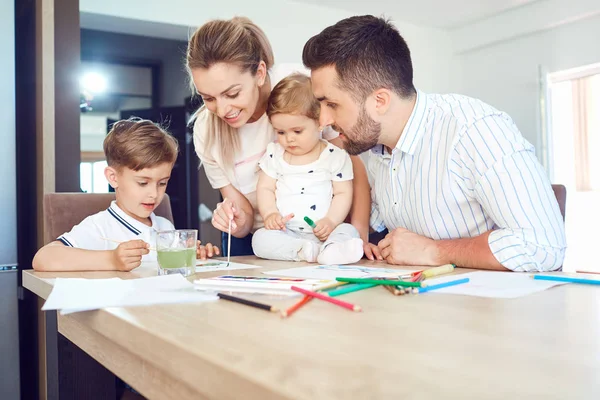 Ευτυχισμένη οικογένεια αντλεί τα χρώματα σε ένα χαρτί στο τραπέζι. — Φωτογραφία Αρχείου