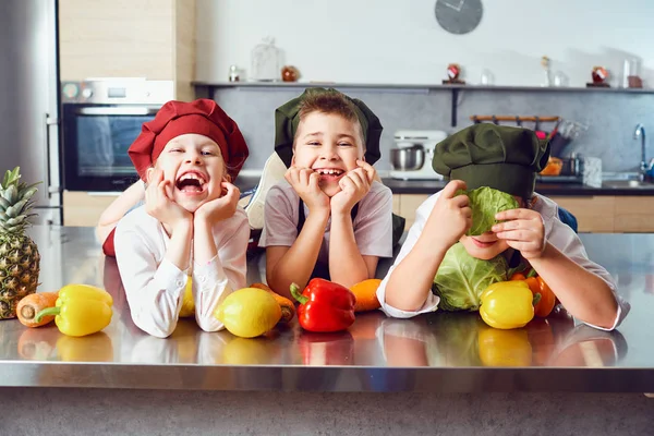 Crianças engraçadas no uniforme de cozinheiros na cozinha . — Fotografia de Stock