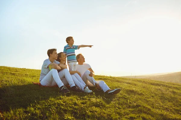 Mutlu aile güneşin batımında doğada oturan. — Stok fotoğraf