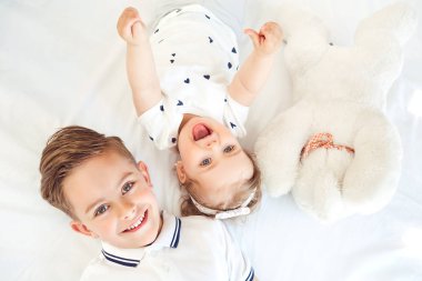 Pozitif çocuk beyaz bir yatakta yatarken gülümseyen. 