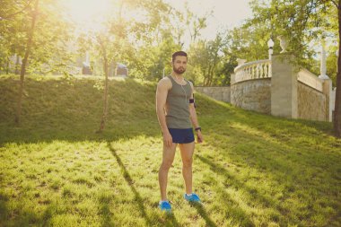 Bir koşucu adam parkta günbatımında duruyor..