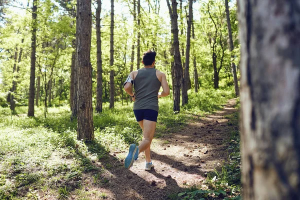 A young male runner runs in the forest. — Stock Photo, Image