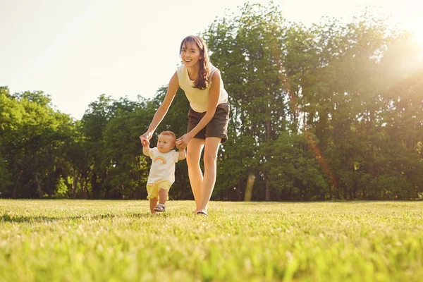 Moeder en kind lopen in het park bij zonsondergang . — Stockfoto