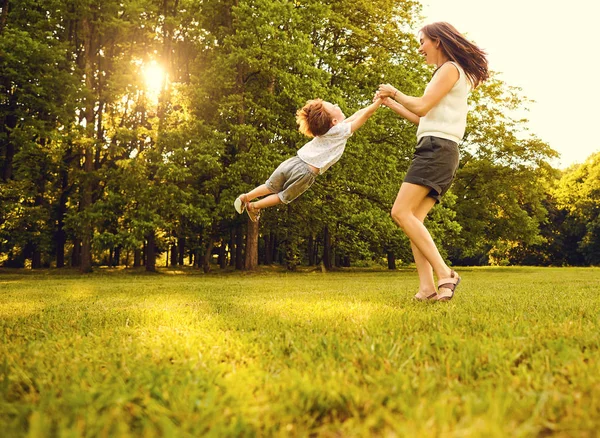 Moeder met kind spelen in het park bij zonsondergang. — Stockfoto