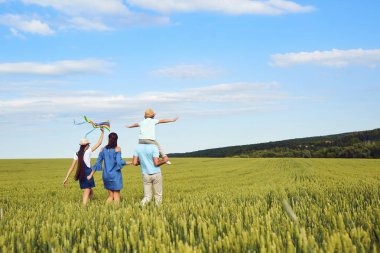 Mutlu bir aile bir buğday alanına yürüyor. 
