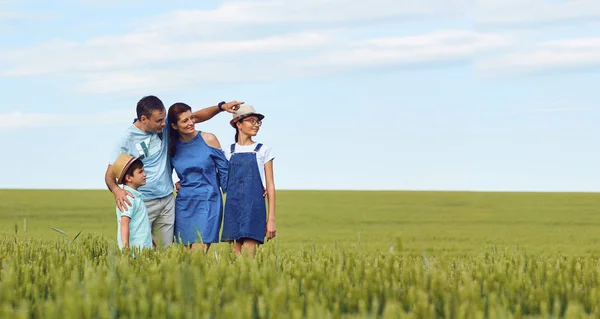 A happy family standing in a wheat field in summer. — Stock Photo, Image