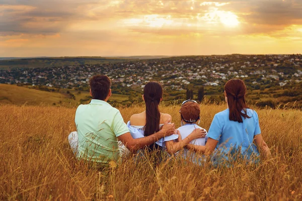 Family sitting  in nature looking at beautiful sunset. — Stock Photo, Image