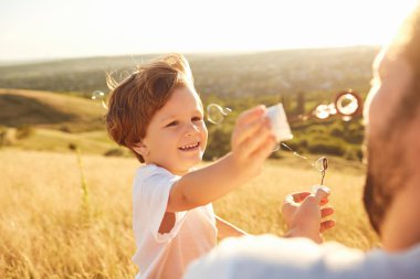 Baba ve oğul doğada sabun köpüğü ile oynamak