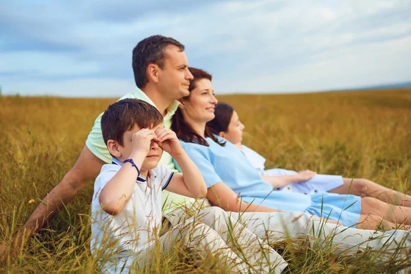 Rodina, odpočívá, společně sedí na trávě v přírodě. — Stock fotografie