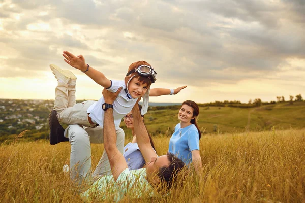 Familia feliz jugando en la hierba en la naturaleza al atardecer — Foto de Stock