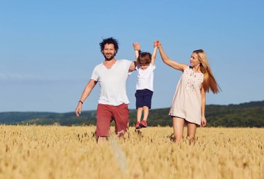 Mutlu bir aile eğlenceli bir çocukla açık havada keyif alıyor.