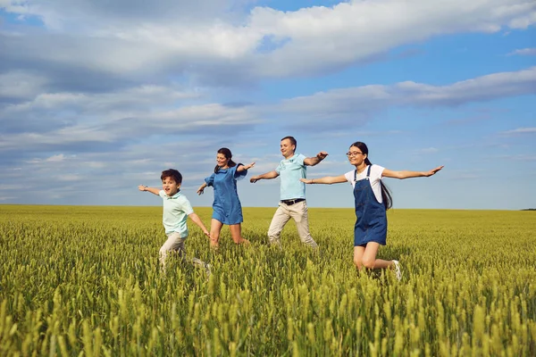 Šťastná rodina s úsměvem, běží na pole v přírodě — Stock fotografie