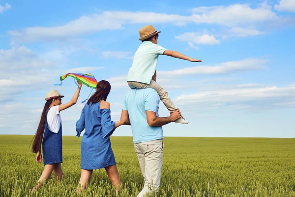 Familie met een vlieger die lopen op het veld in de natuur. — Stockfoto