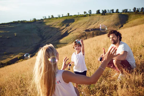 A család játszik a szappanbuborékok, a természetben — Stock Fotó