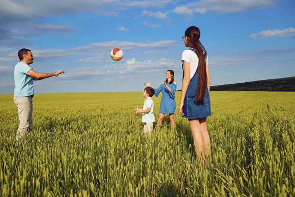 Familia feliz jugando con pelota en el campo de verano — Foto de Stock