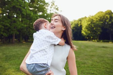 Anne ve oğlu parkta sarılıyorlar. 
