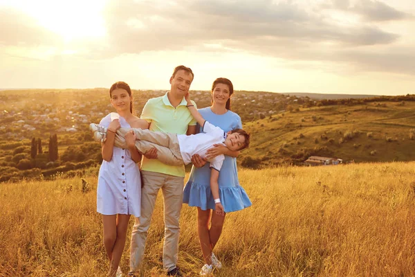 Retrato de uma família feliz sentada na natureza na grama . — Fotografia de Stock