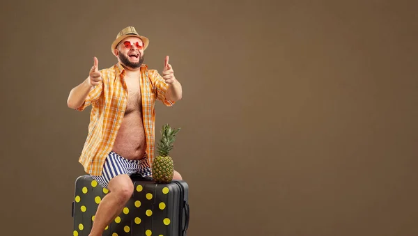 Un om gras amuzant de echitatie o valiză într-o vacanță de vară . — Fotografie, imagine de stoc