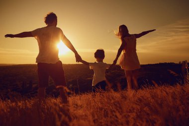 Gün batımında doğada aile ayakta arkadan görünüş