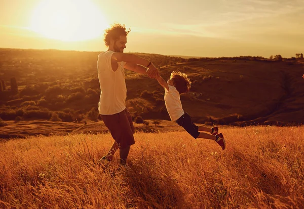 Père et enfant jouant dans la nature au coucher du soleil . — Photo