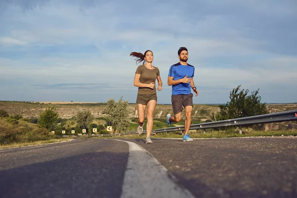 Un chico y una chica trotan por la carretera en la naturaleza . —  Fotos de Stock