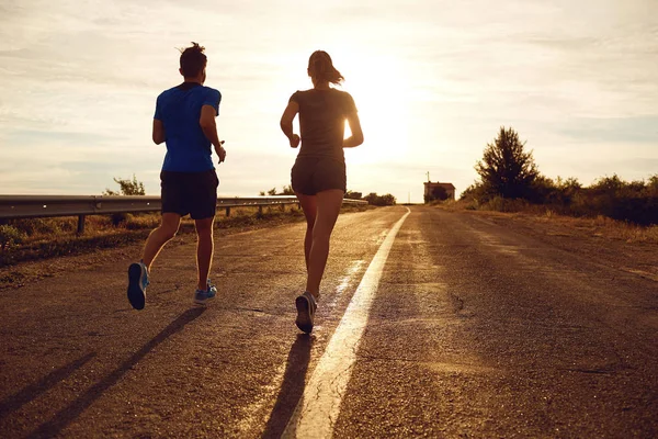 A guy and a girl jog along the road  in nature. — Stock Photo, Image
