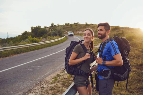 Boldog pár turista mosolyogva az úton, a természetben. — Stock Fotó