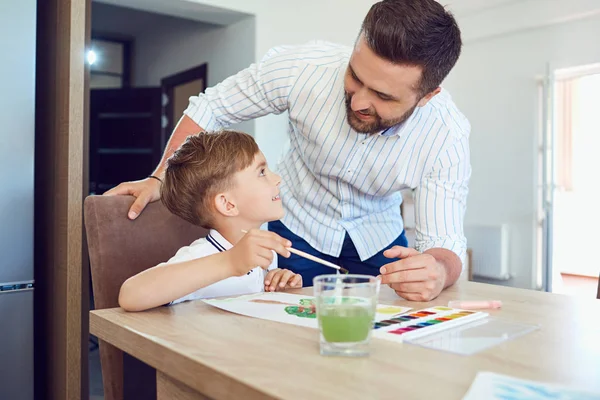 テーブルに紙の上の父と息子のペイント. — ストック写真