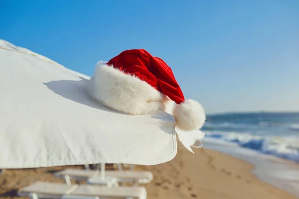 Cappello Babbo Natale sulla spiaggia in riva al mare. Natale in vacanza b — Foto Stock