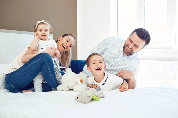 Happy family  playing lying on the bed in the bedroom. — Stock Photo, Image