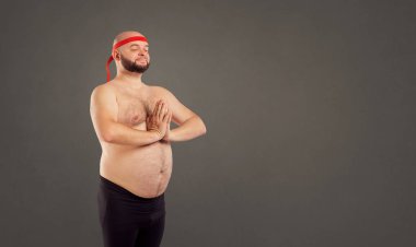 Yoga yaparken çıplak midesi olan sakallı bir adam.