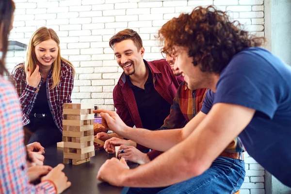 Eine fröhliche Gruppe junger Leute spielt Brettspiele. — Stockfoto