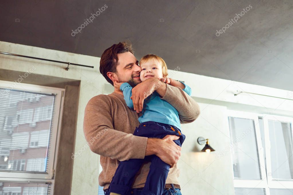 Father and son play hugs in the room. 