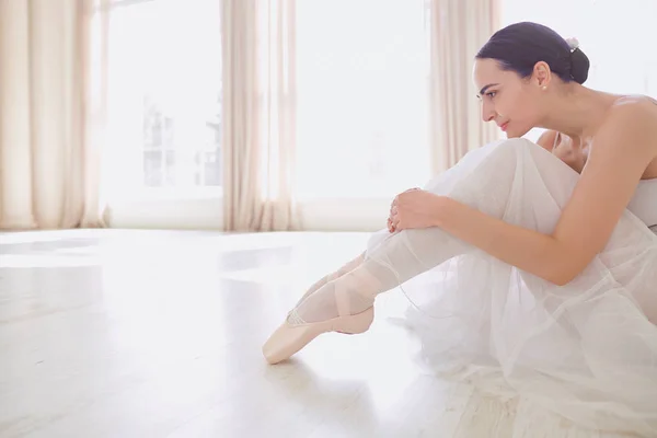 Uma bailarina com roupas brancas em um estúdio branco . — Fotografia de Stock