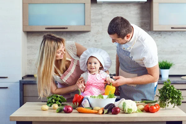 A happy family prepares food from vegetables in the kitchen — Stock Photo, Image