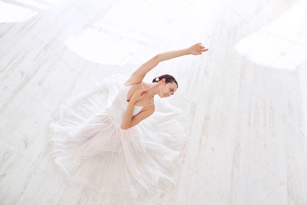 A ballerina in white clothes in a white studio.