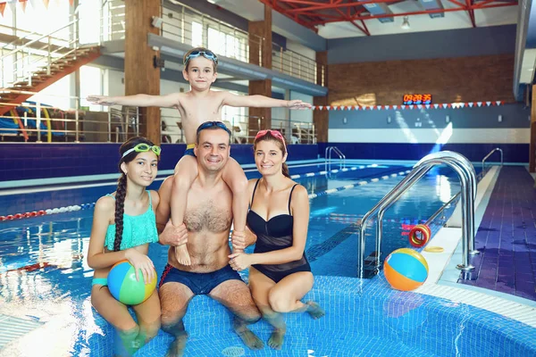 O familie fericită zâmbește într-o piscină . — Fotografie, imagine de stoc
