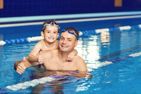 Jonge vader en zijn zoontje in een overdekt zwembad. — Stockfoto