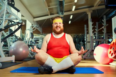 Komik şişman adam spor salonunda yoga yaparken sakallı
