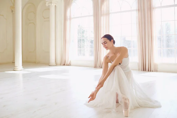Une ballerine en vêtements blancs dans un studio blanc . — Photo