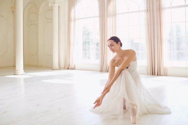 Uma bailarina com roupas brancas em um estúdio branco . — Fotografia de Stock