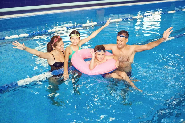 Una familia feliz sonríe en una piscina . —  Fotos de Stock