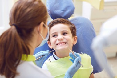 A child with a dentist in a dental office.  clipart