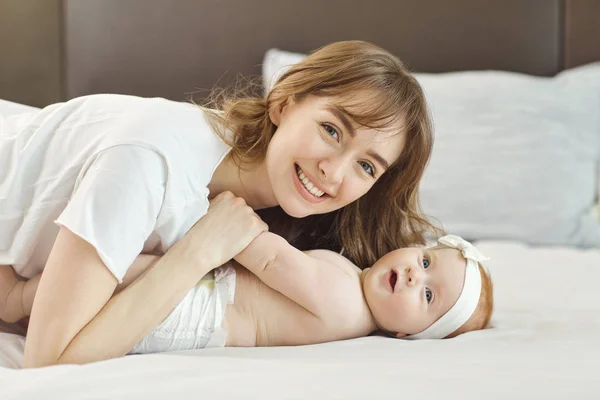 Moeder spelen met baby op het bed. — Stockfoto