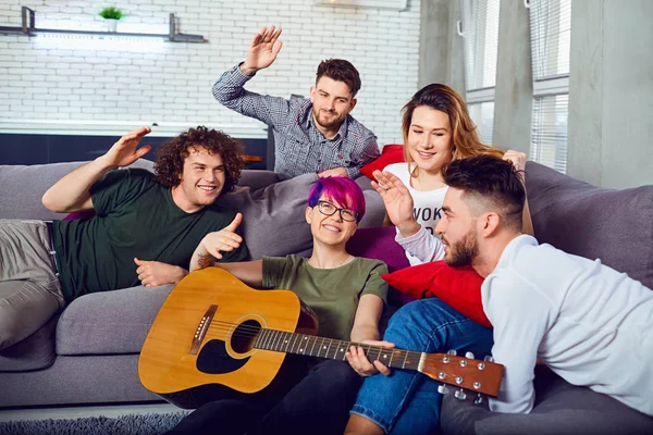 Gruppe von Freunden mit einer Gitarre auf einer Party in einem Raum. — Stockfoto