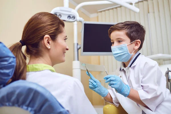 一个男孩是个牙医, 在牙科诊所有个病人。 — 图库照片