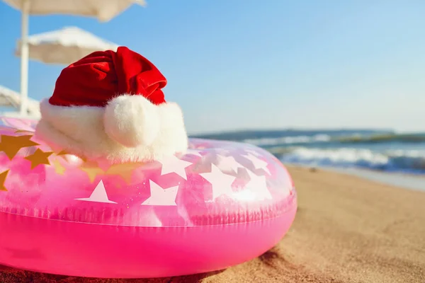Czapka Świętego Mikołaja na plaży nad morzem. Boże Narodzenie na wakacje b — Zdjęcie stockowe
