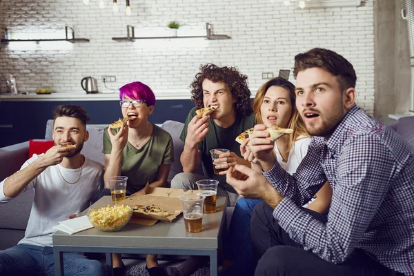 Een groep vrienden eten pizza zittend op de Bank. — Stockfoto